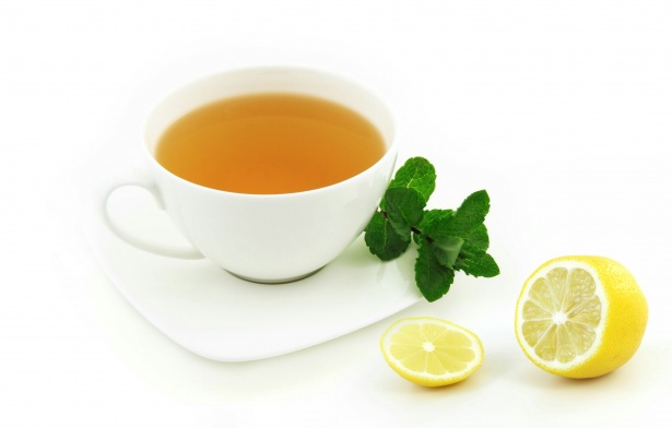 白いカップに入った薄い紅茶とレモンとミントの画像です。
