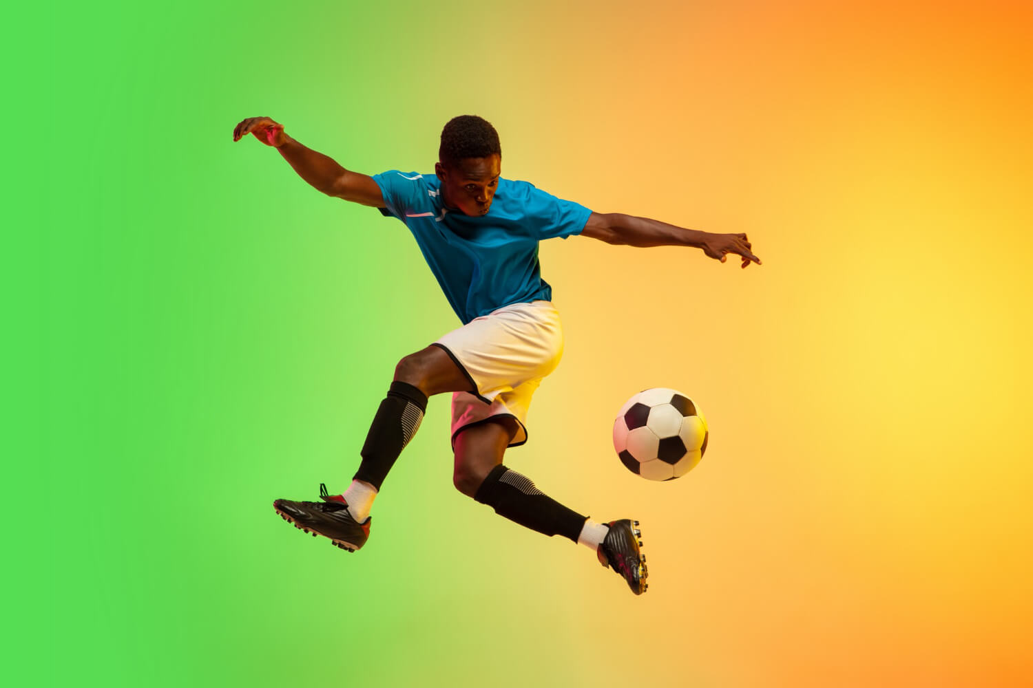 Jogador de futebol profissional no ar, chutando uma bola de futebol