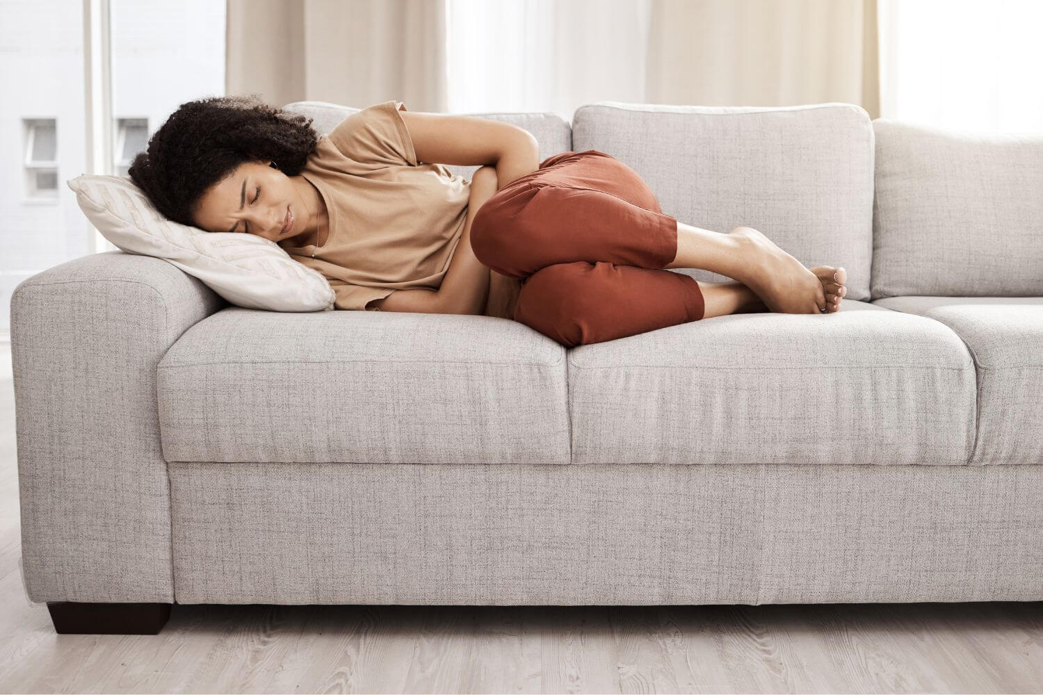Woman in pain laying on a couch in the fetal position