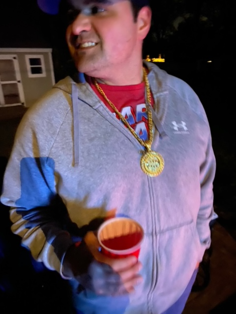 A person wearing a hoodie and a gold necklace holding a red cup

Description automatically generated