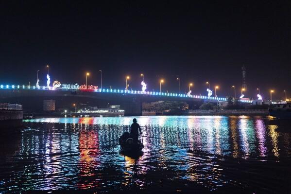 Nguyen Thi Thuy, a vendor who sells steamed buns at a floating market, pauses her paddle briefly on her way to the market before sunrise in Can Tho, Vietnam, Wednesday, Jan. 17, 2024. (AP Photo/Jae C. Hong)