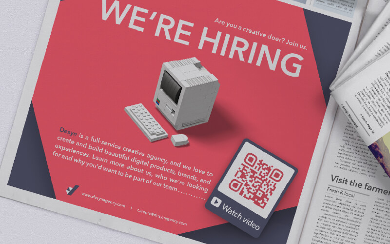 A QR Code in a print newspaper ad prompting readers to scan to watch an informational company video