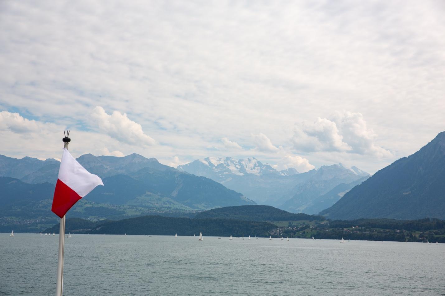 A flag on a boat in front of mountains

Description automatically generated