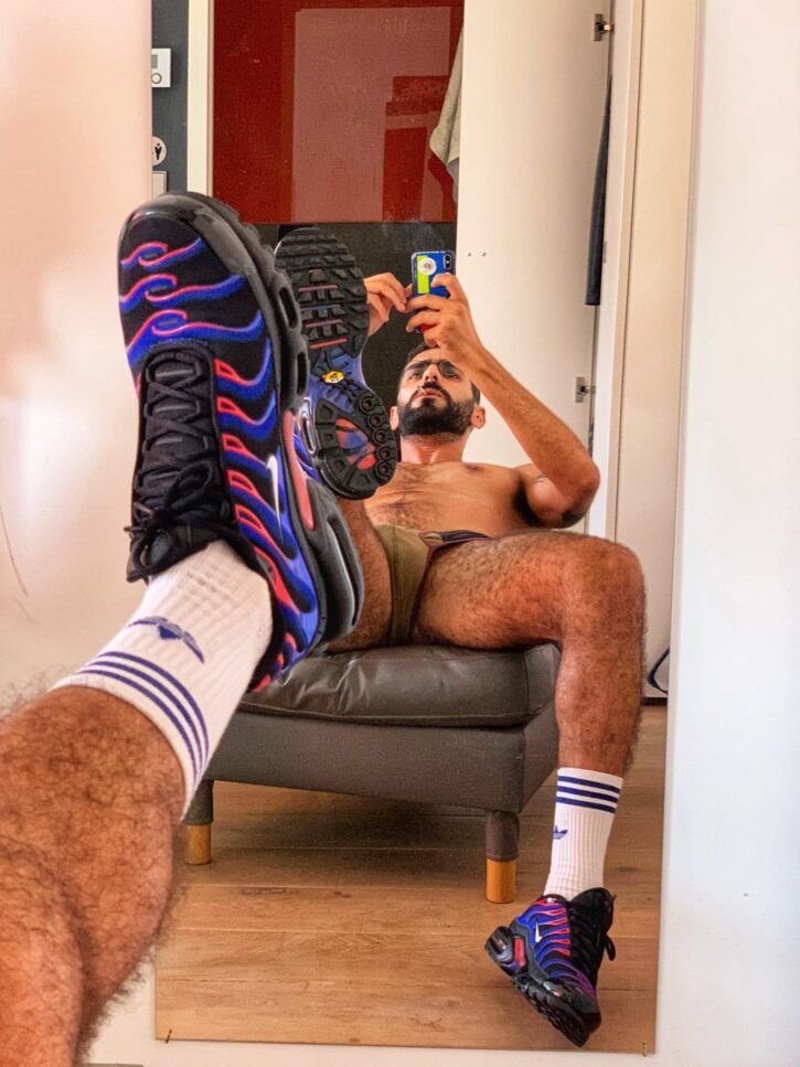 karim yoav leaning against the mirror in his underwear showing off his athletic socks and running shoes