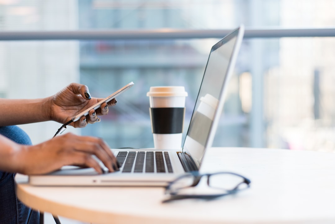 A person using smartphone and MacBook.