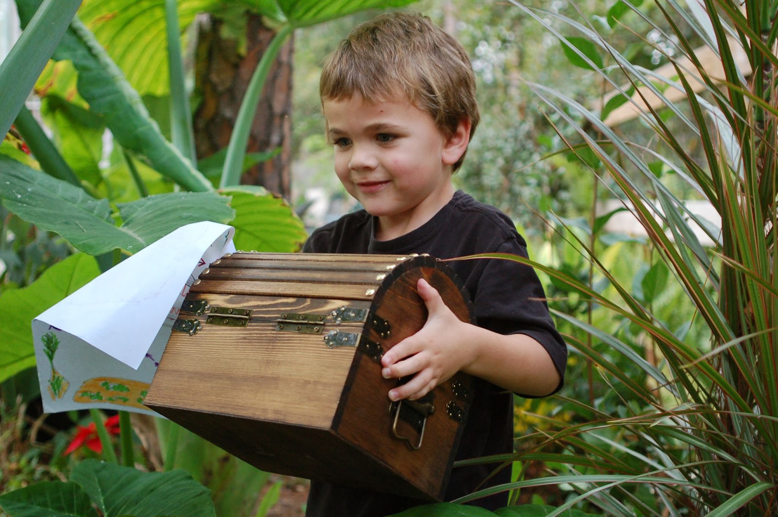A happy kid carrying a treasure chest box in an outdoor setting.  