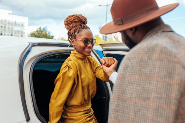 smiling classy woman entering limousine. - lovers african  stock pictures, royalty-free photos & images