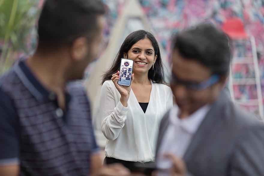 A women holding a phone with the New York Mets Wallpaper schedule on it. 