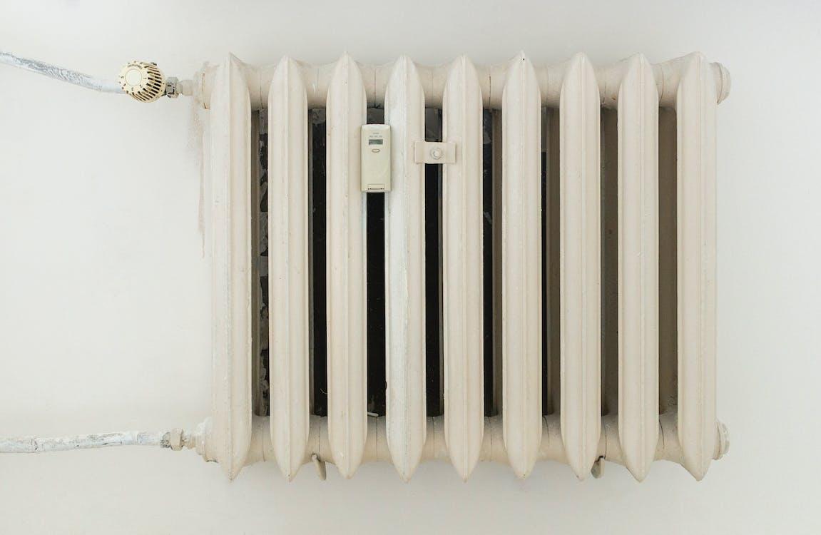 Free White steel rib radiator in a new bright renovated room in apartment or home Stock Photo
