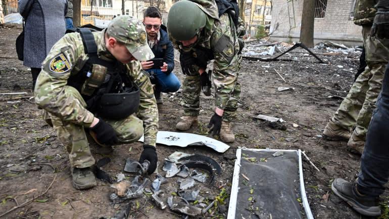 A group of soldiers looking at broken pieces of metal