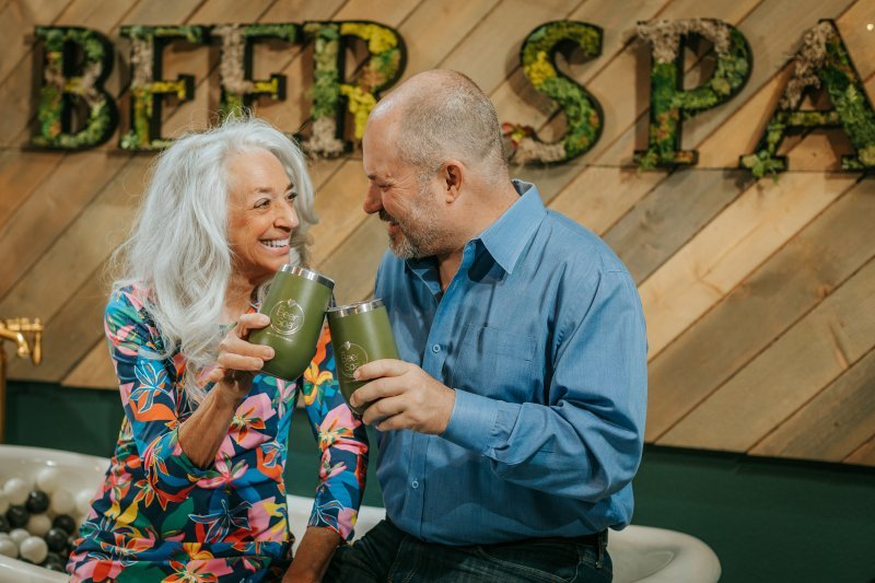 couple smiling at each other and holding tumblers at Oakwell Beer Spa