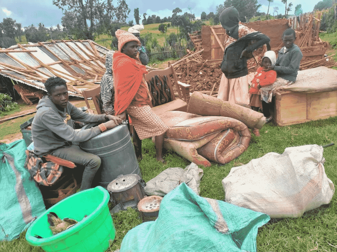 A family of five sit among their few possessions laid out on the grass beside their demolished home.