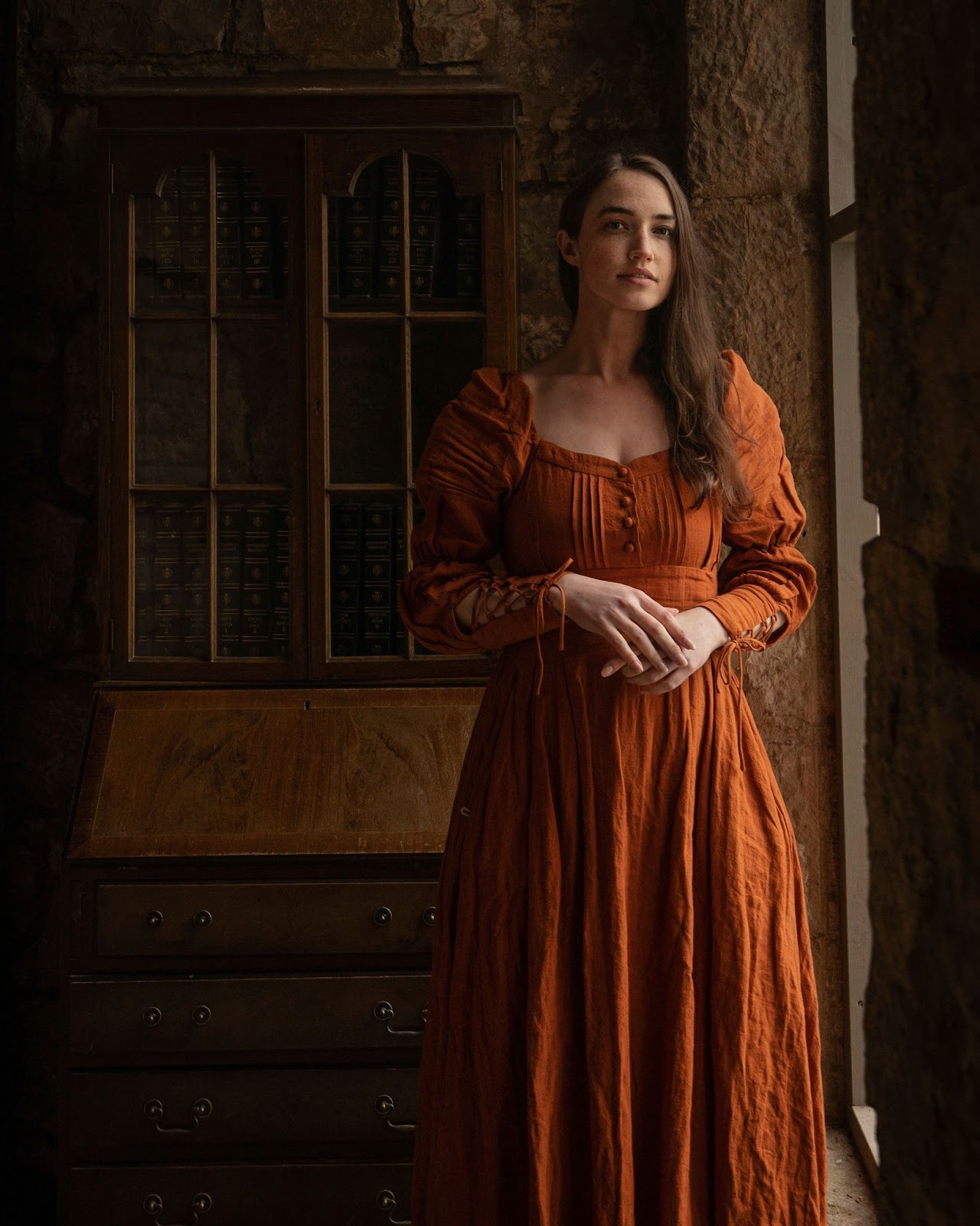 A woman posing in front of an antique almirah for her modelling headshot.