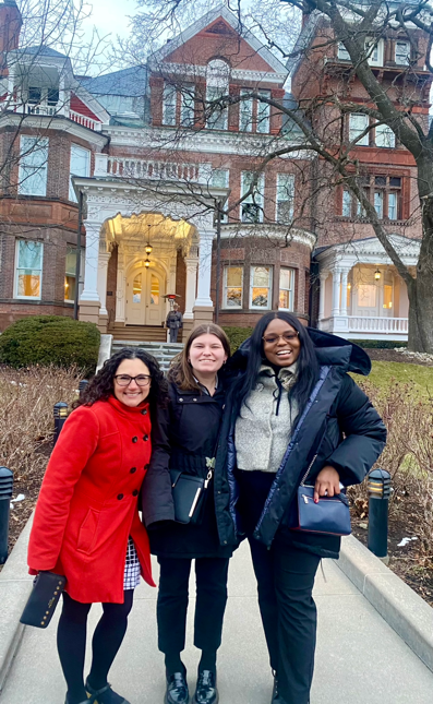 A group of women standing in front of a house  Description automatically generated