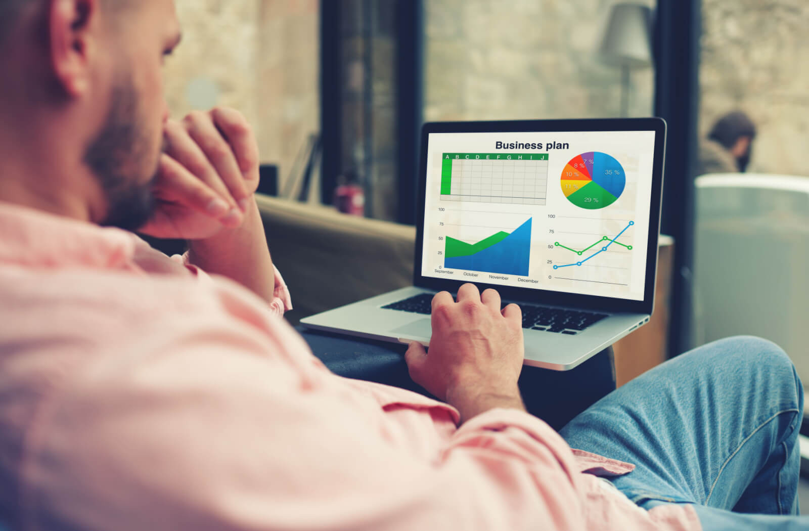 An experienced business man examining financial data presented through graphs and charts on his laptop.