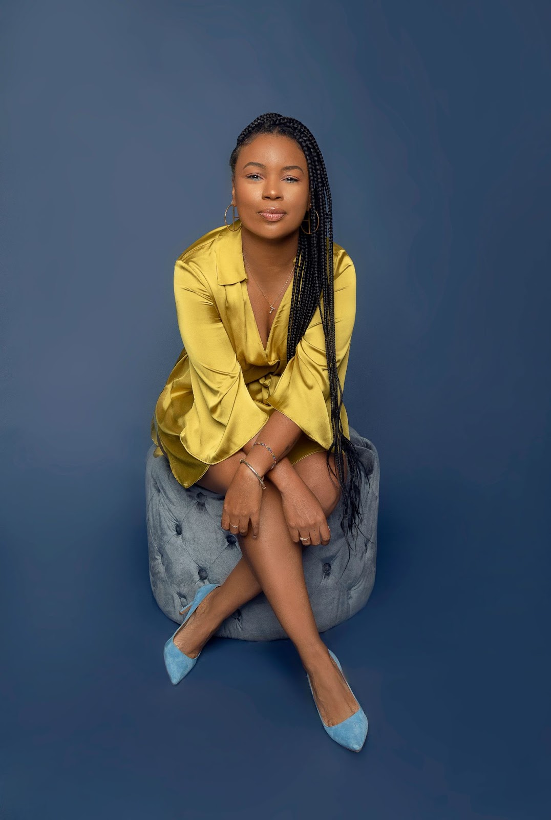 A woman is exuding confidence and power through her pose while sitting on a chair.