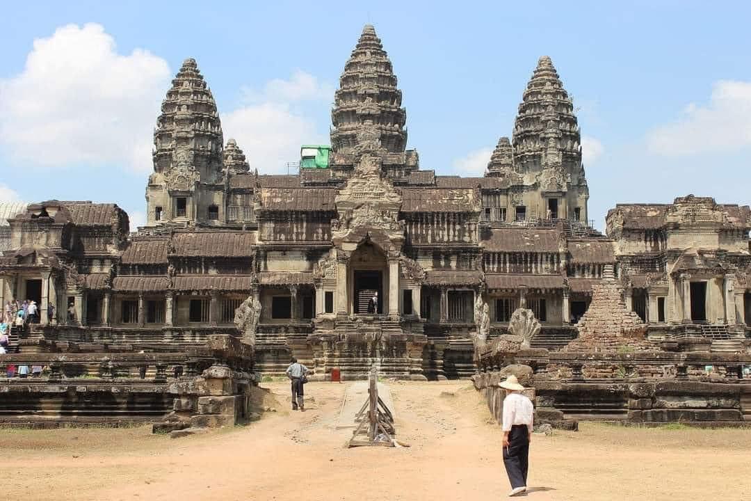 A person walking in front of Angkor Wat

Description automatically generated