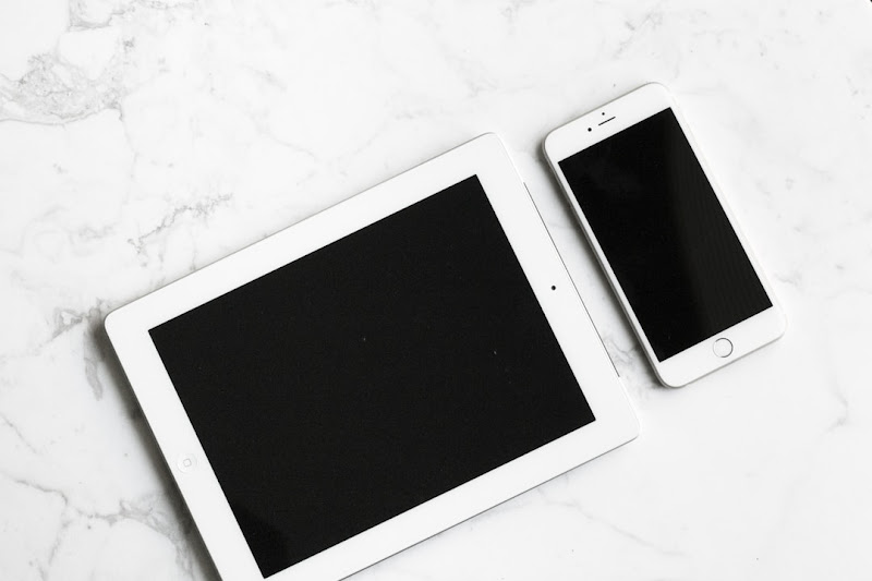 A tablet and a smartphone rest on top of a sleek granite table.