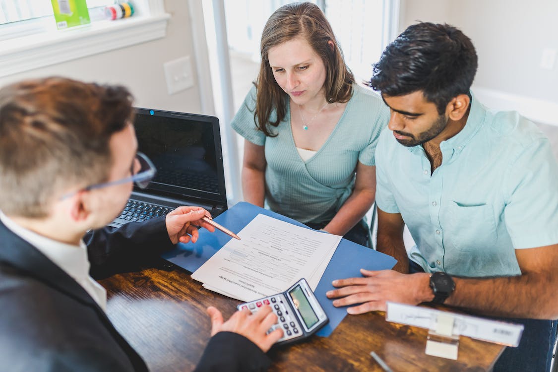 Free Real Estate Agent in Black Coat Discussing an Ownership Agreement to a Couple Inside  the Office Stock Photo