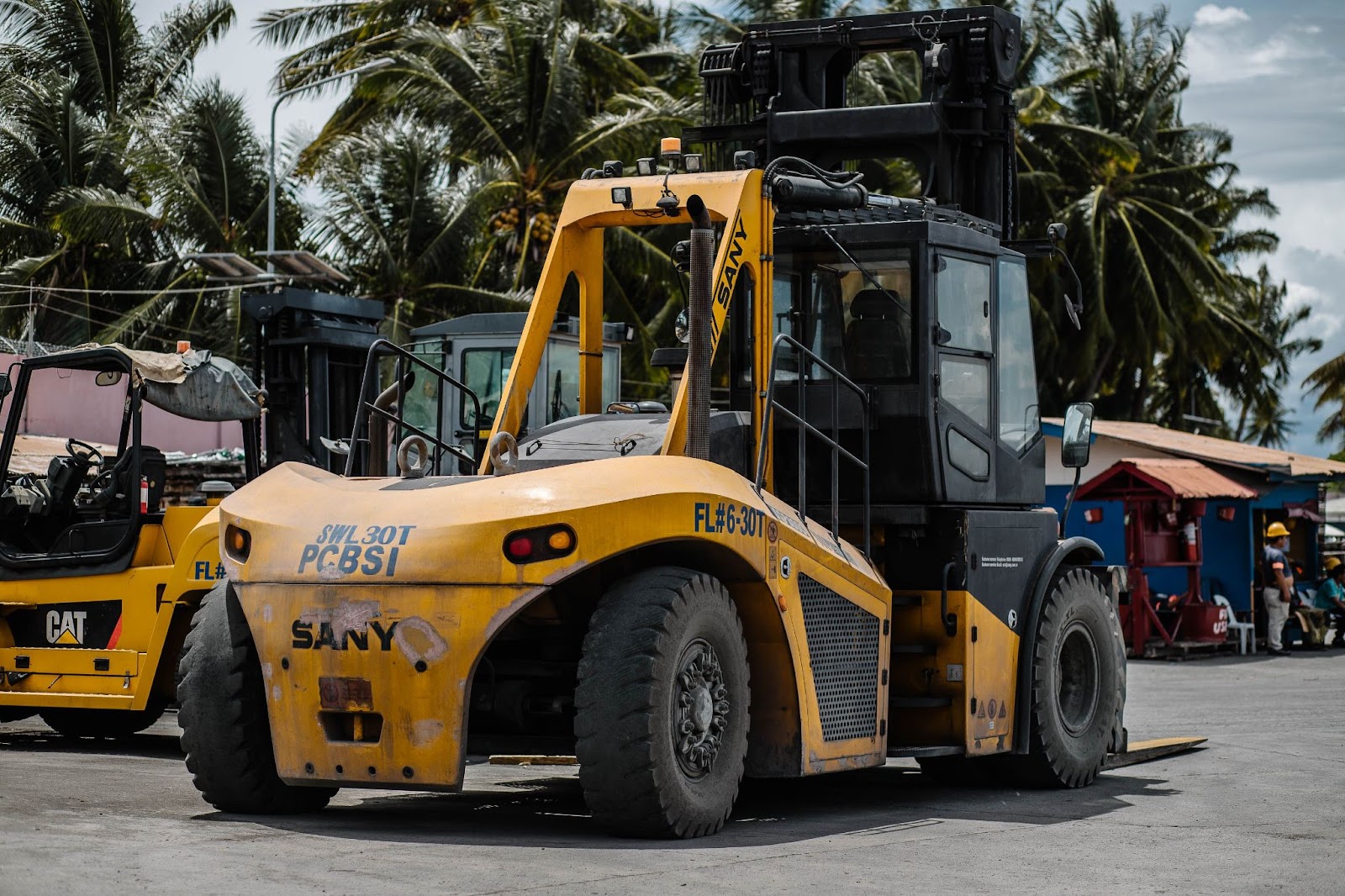 A yellow CAT forklift with pneumatic tires on an asphalt road
