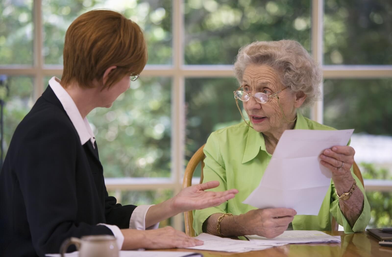 An older woman holds a piece of paper while his lawyer talks about what's written on it.
