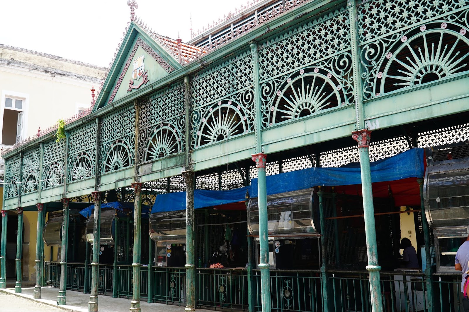 Um dos lados da fachada do Mercado Ver-o-Peso, em Belém. As barraquinhas de vendas são protegidas por um grande telhado de ferro esverdeado com elaborados detalhes vazados