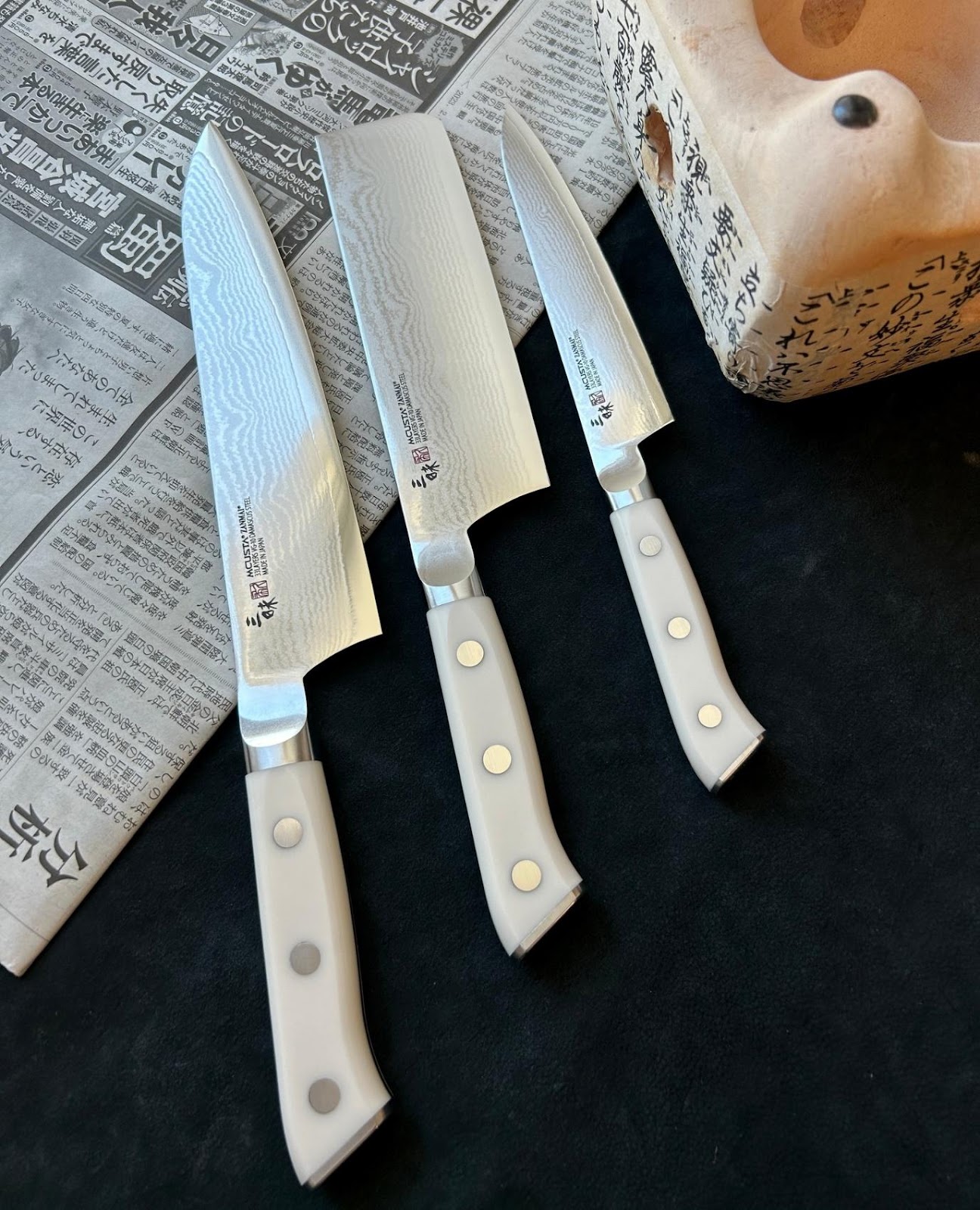 A group of knives on a newspaper

Description automatically generated