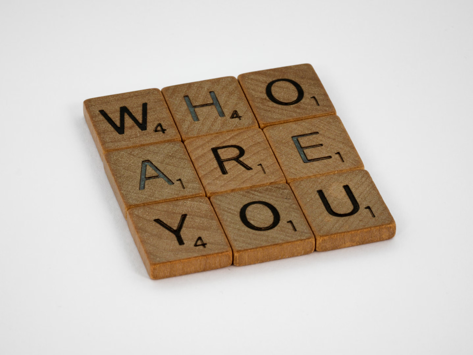 Brown wooden puzzle made of square blocks, showing the word 'WHO ARE YOU'