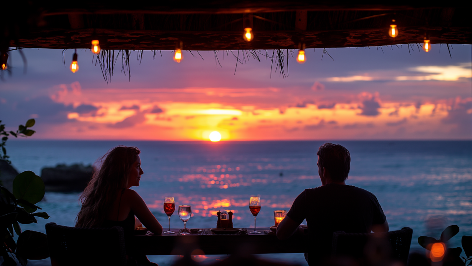 A couple enjoys a romantic dinner at an upscale restaurant with ocean views in Playa del Carmen.