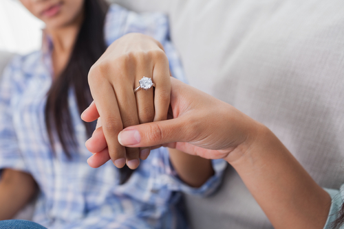 Hand showing off a woman wearing a diamond engagement ring on her fingers