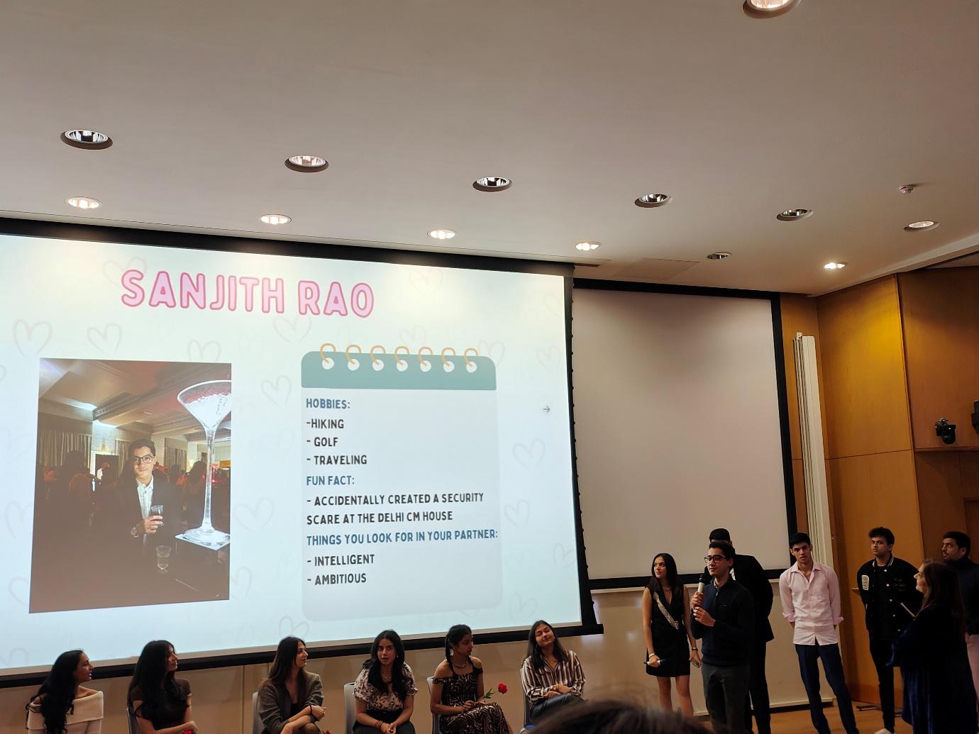 A group of people standing in front of a large screen

Description automatically generated