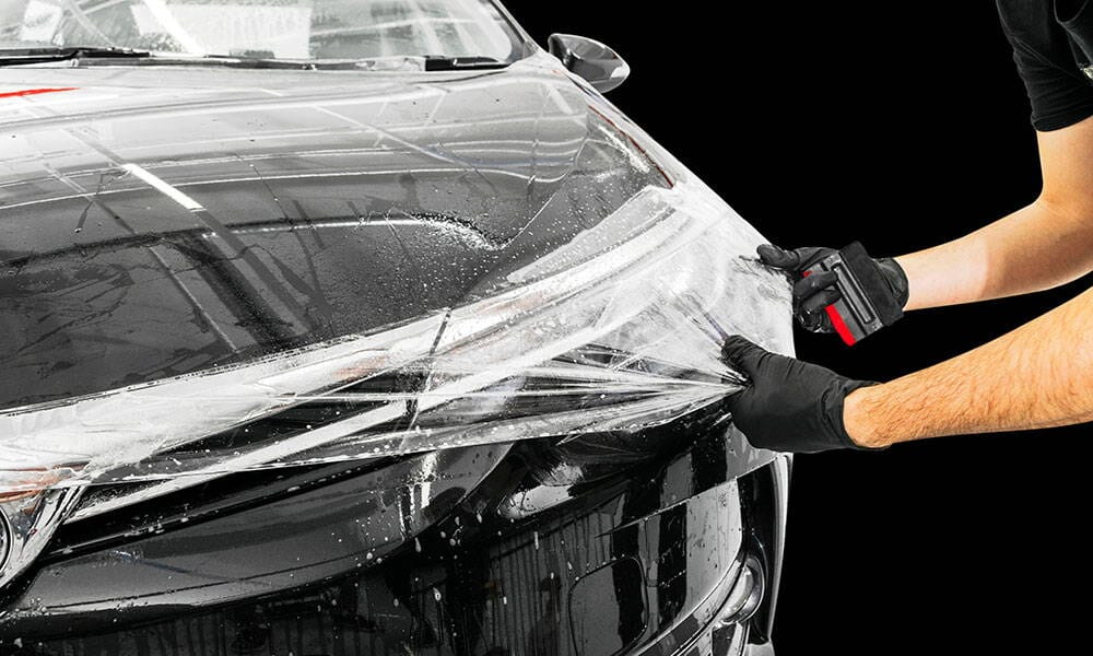 A person is applying tint to a car wrap.