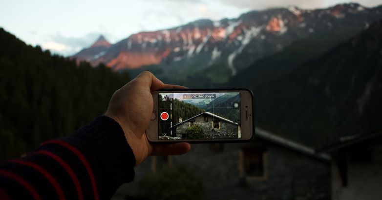 A tourist live streaming while traveling in a beautiful place with stunning view of the mountains
