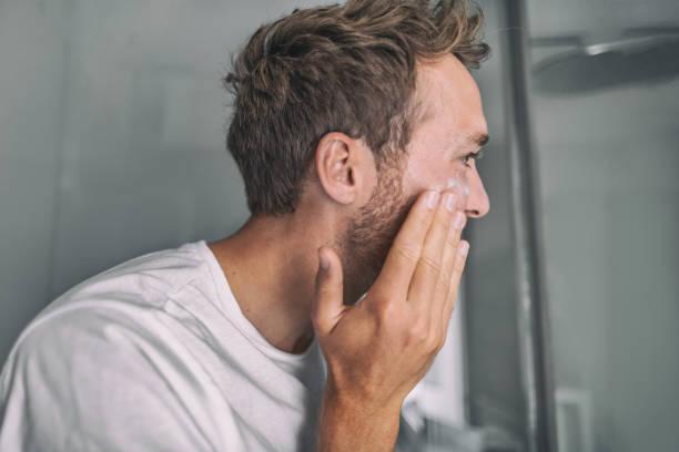 Skin care young man putting face cream for facial acne treatment in home bathroom. Men beauty skincare lifestyle Skin care young man putting face cream for facial acne treatment in home bathroom. Men beauty skincare lifestyle. eczema face cream stock pictures, royalty-free photos & images