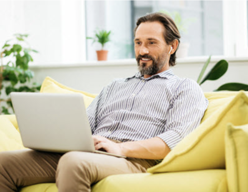 A person sitting on a couch using a computerDescription automatically generated