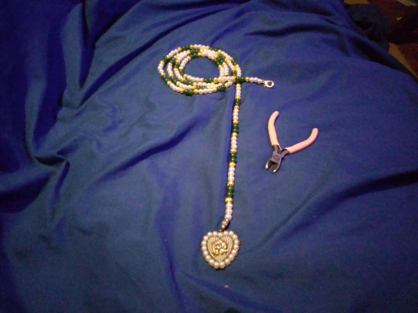 A necklace and a pliers on a blue blanket

Description automatically generated