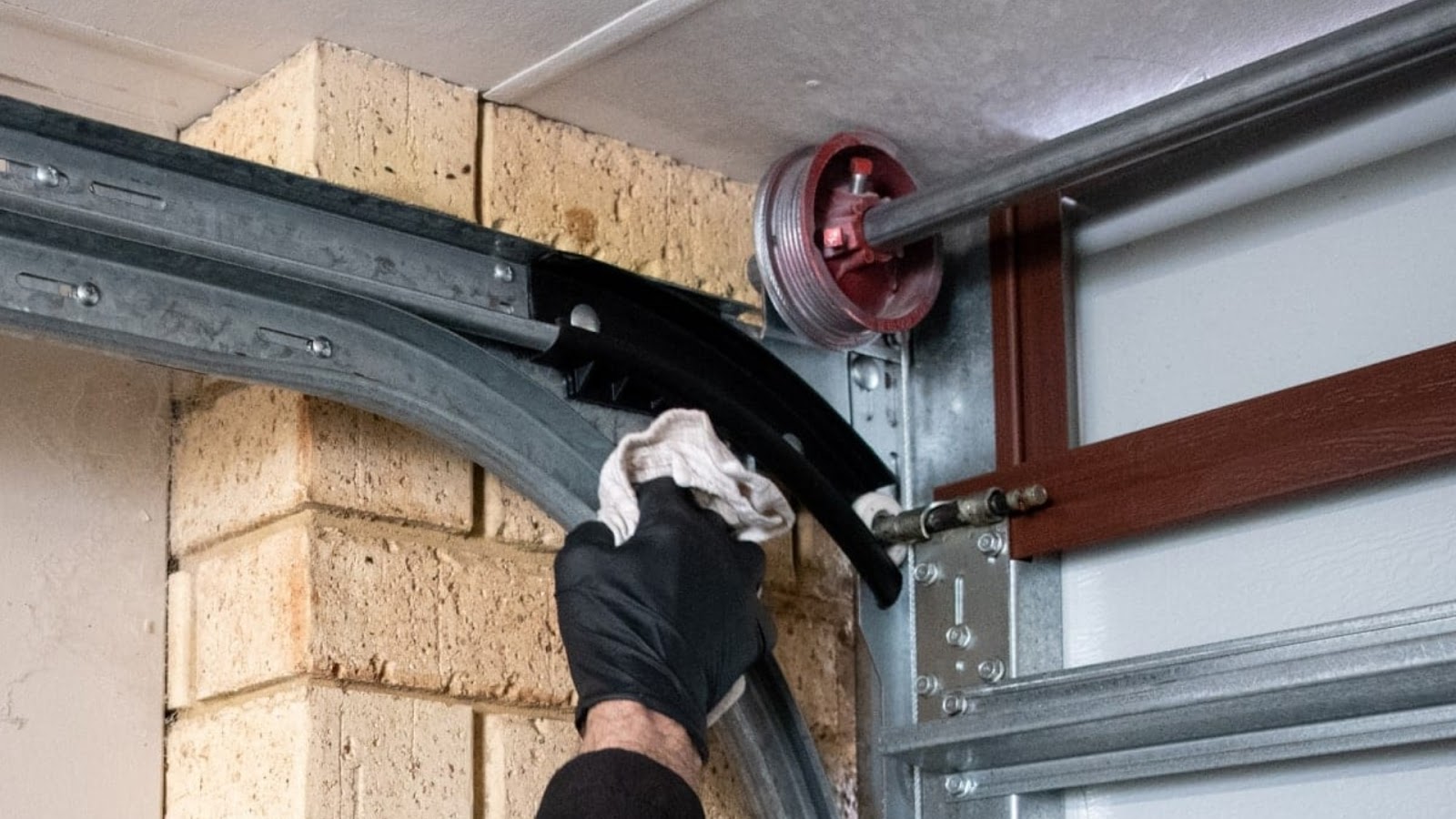 A homeowner cleaning the tracks of a slow garage door 