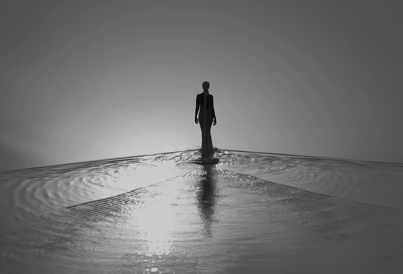 A desaturated screenshot of Kelela from her music video for "Washed Away". Featuring a shot of her walking across a salt lake at the Danakil Depression, in a white dress and a headwrap with a long train.