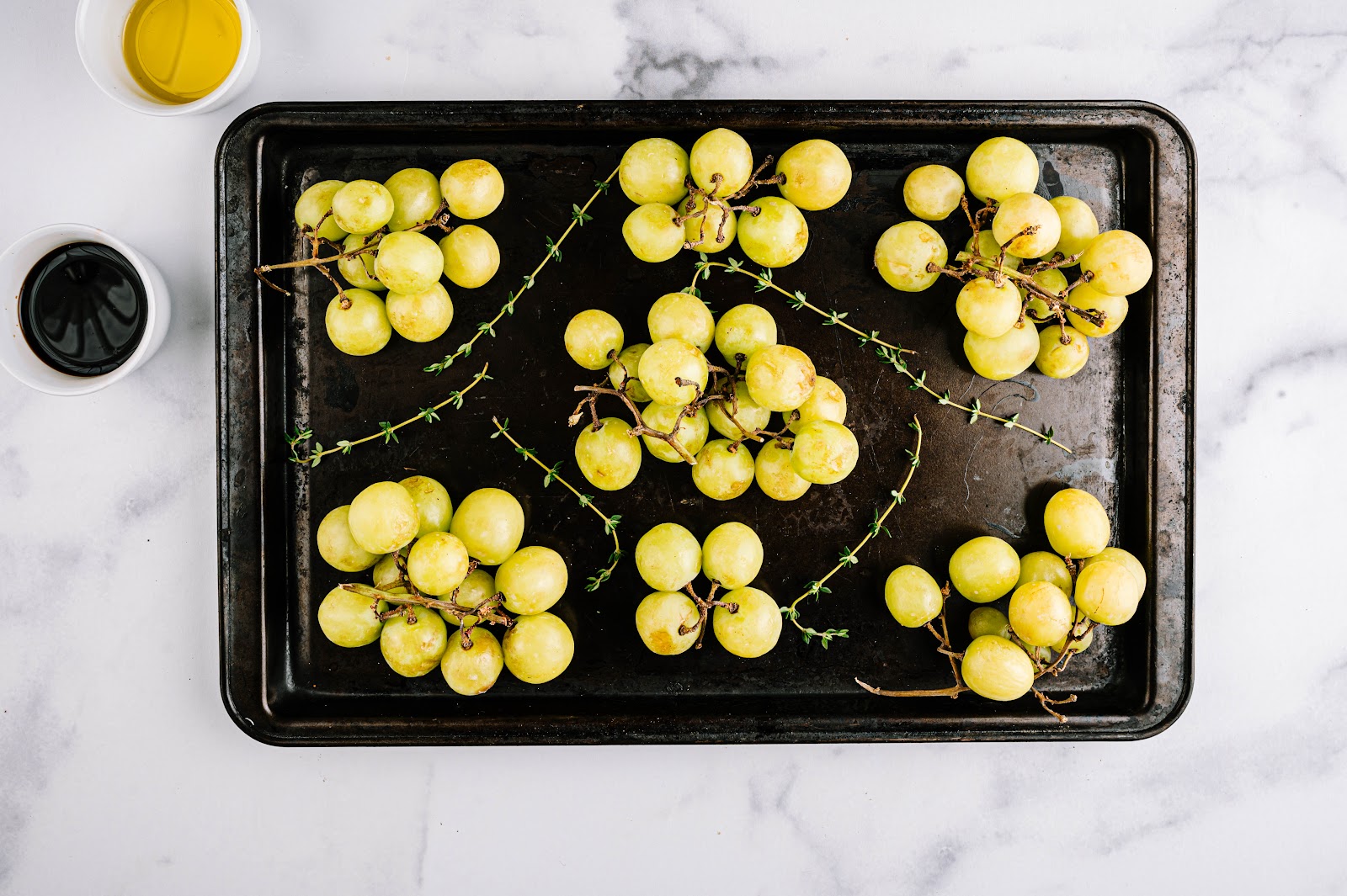 Place grapes and thyme on baking sheet and drizzle with oil, vinegar, salt, and pepper.