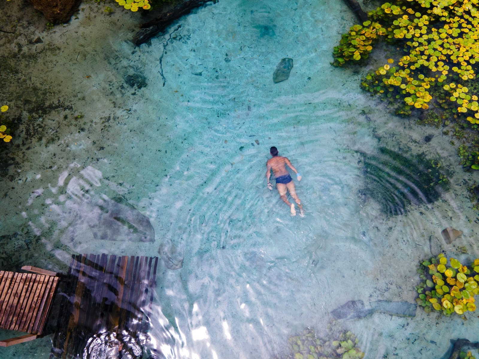 Vista aérea de um homem nadando e um dos lagos espalhados pela Chapada Diamantina