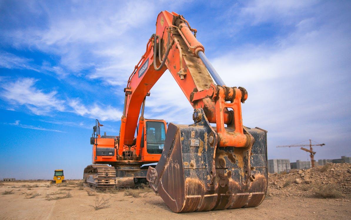 Free Low Angle Photography of Orange Excavator Under White Clouds Stock Photo