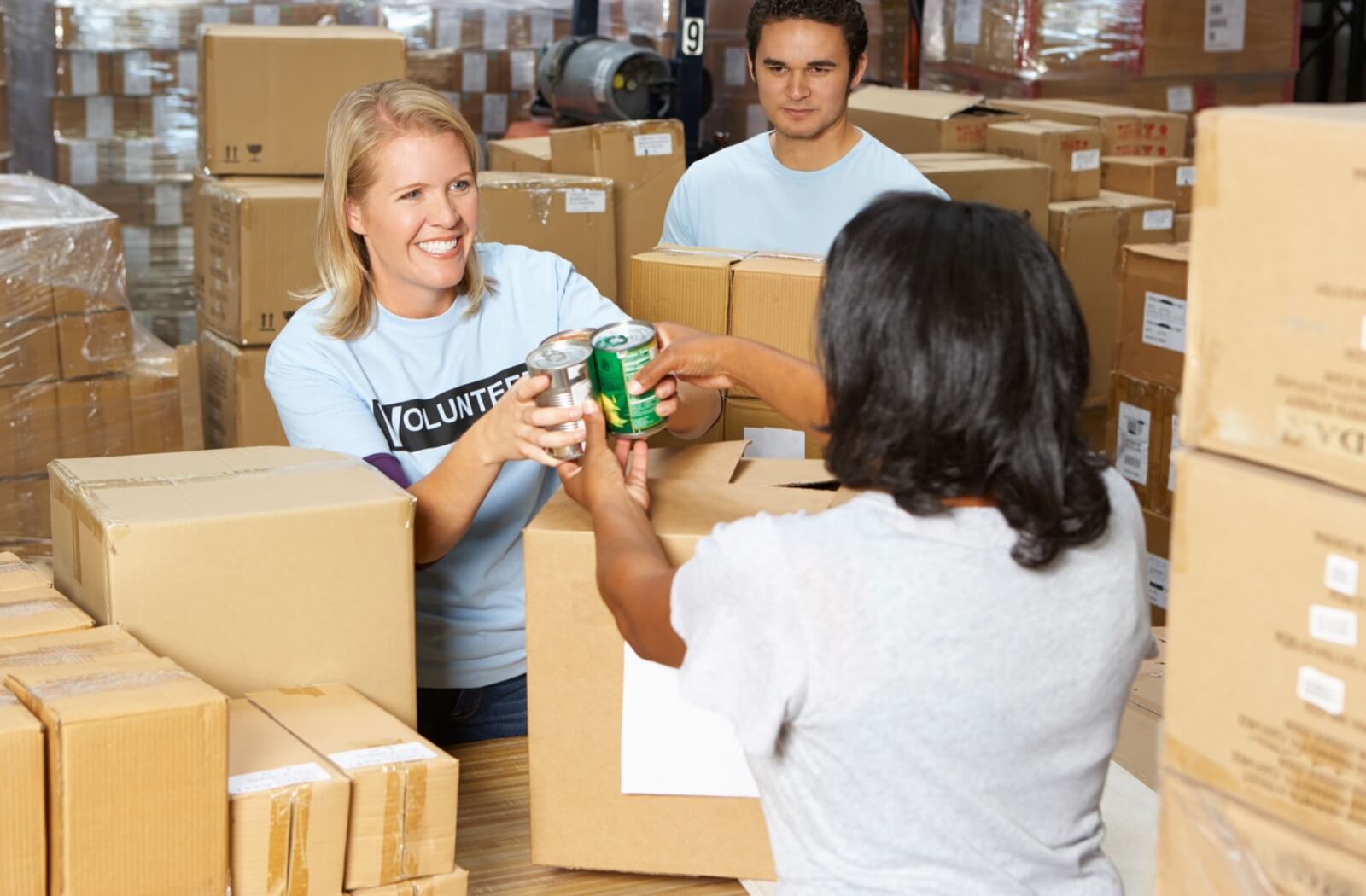 A food bank volunteer receiving the canned goods donation from a woman.