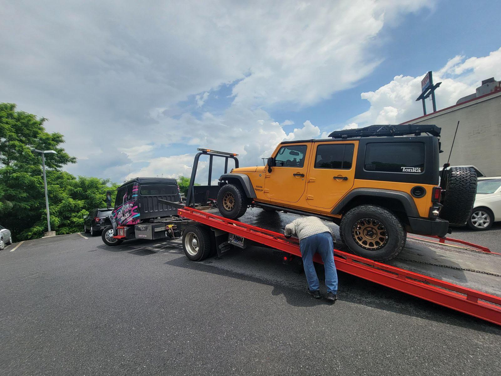 A person lifting a car on a flatbed trailer

Description automatically generated