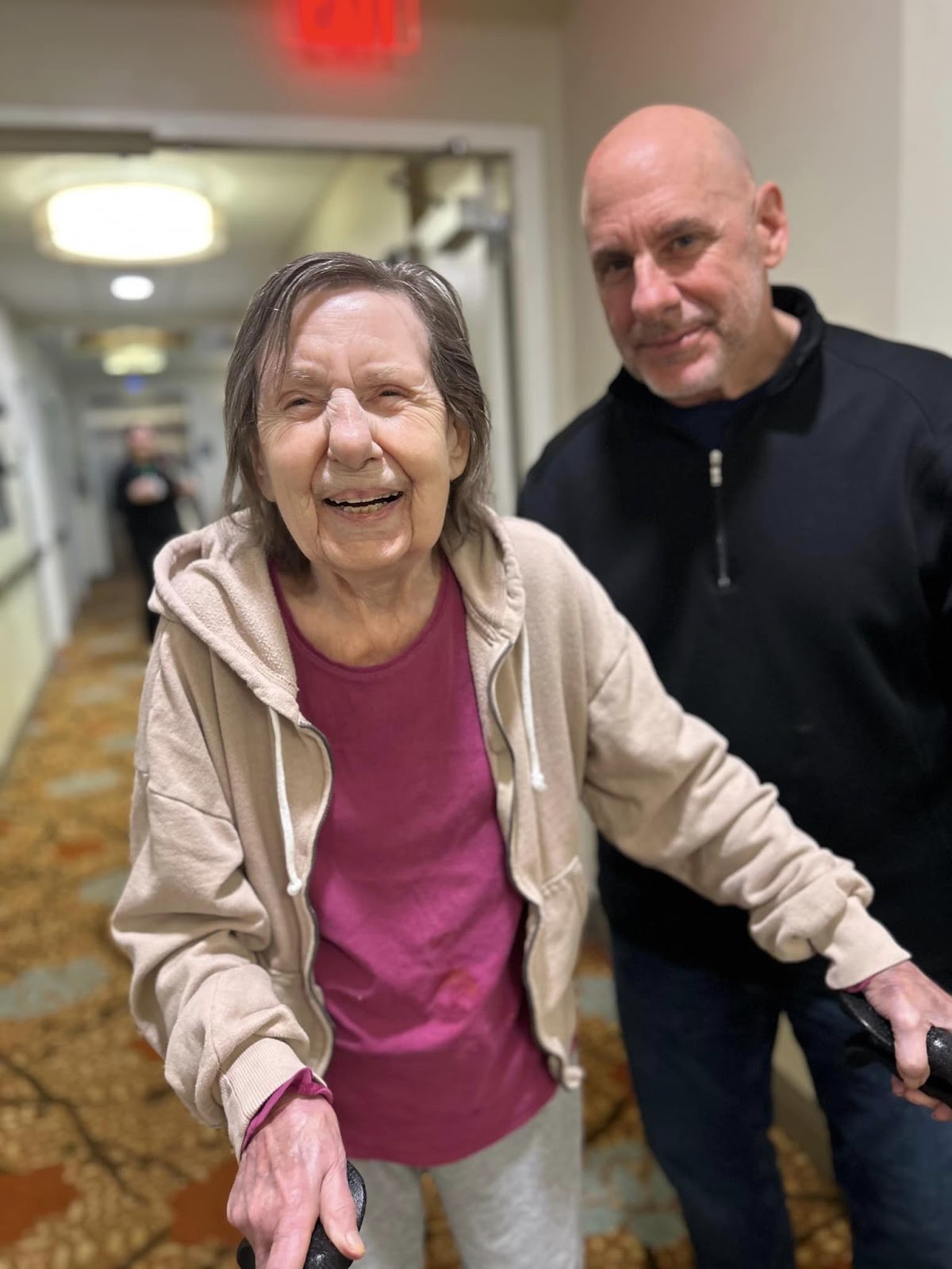 A woman smiling and standing and using a walker to aid her in walking