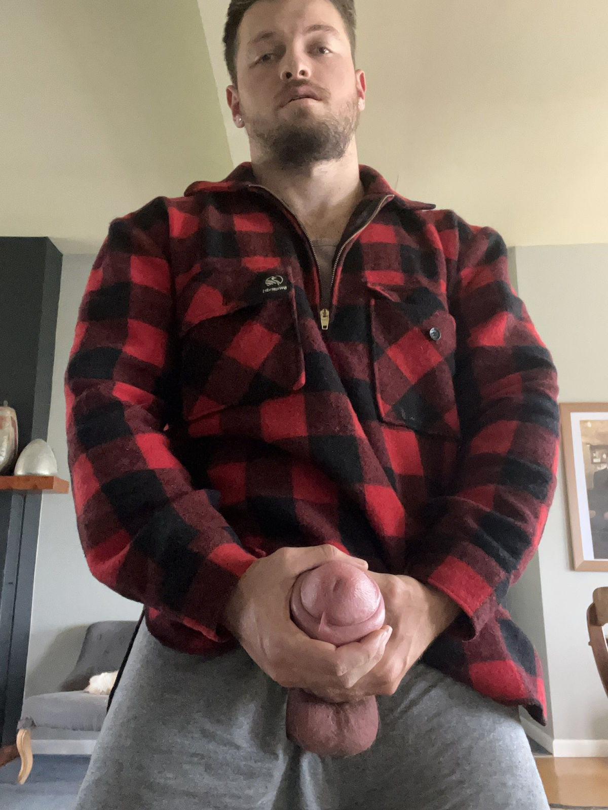 Max Small wearing a red flannel shirt and jeans jerking off his cock through the zipper and the tip of his penis covered in pre cum