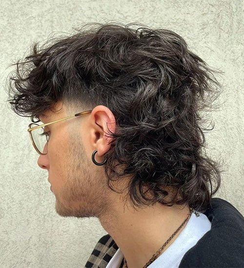 Side picture of a man rocking the  curly wolf cut