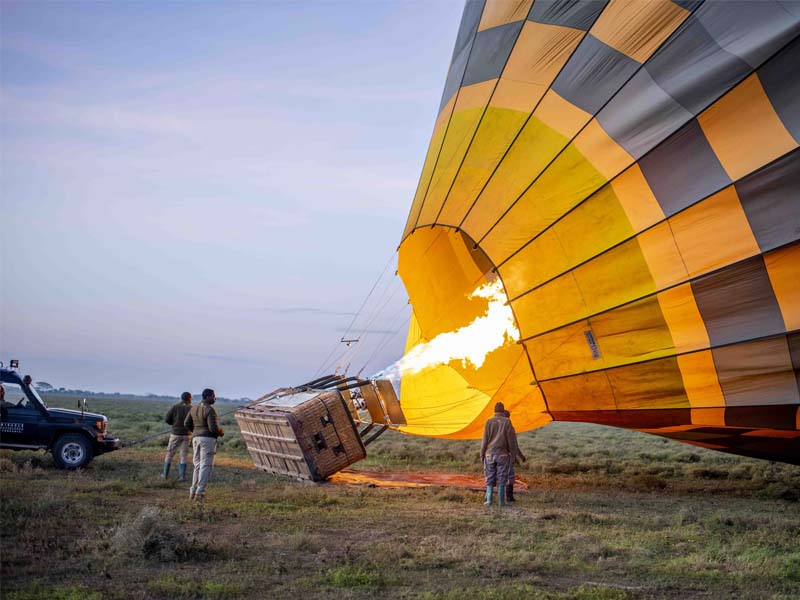 A charming illustration of the ground crew assisting with hot air balloon inflation