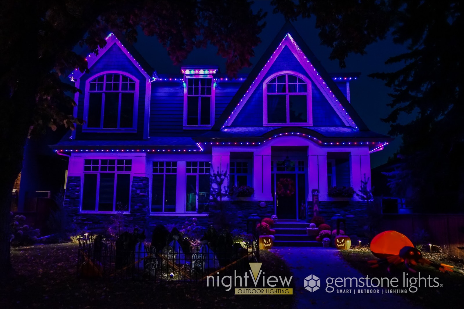 Permanent holiday lighting casts a purple glow on a home during the Halloween season