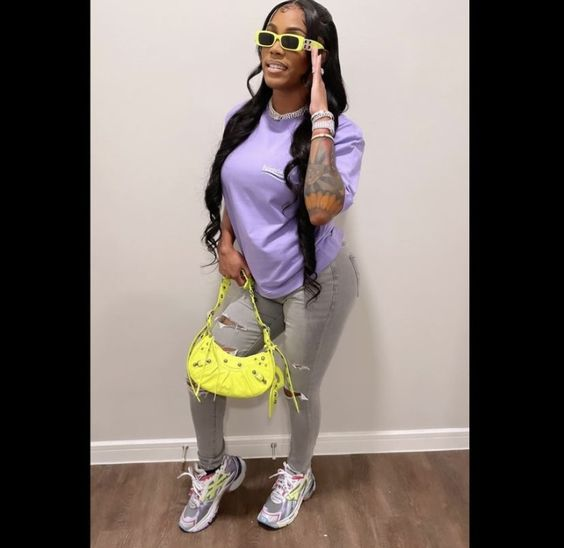 a lady wearing a top with jeans and sneakers with yellow handbag