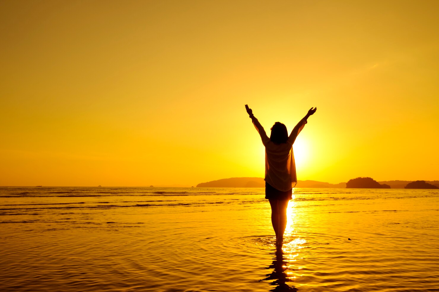 A woman living life standing in water at a beach.